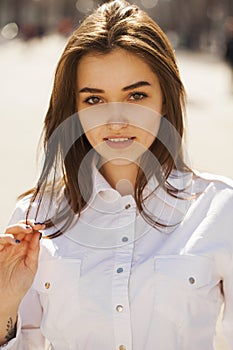 Young beautiful brunette girl in white shirt posing on spring park