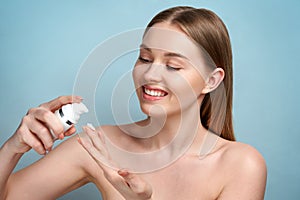 Close-up young beautiful face of girl applying moisturize cream - blue background. Skincare, Perfect skin. Blonde women take face