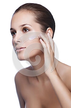 Close-up young beautiful face of girl applying moisturize cream photo