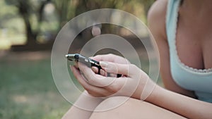 Close Up of Young Beautiful Girl Sitting On Lawn In Park Using Phone, On-line Shopping Concept