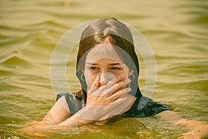 A girl swims in the river. Close up of young beautiful girl in water