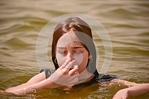 A girl swims in the river. Close up of young beautiful girl in water