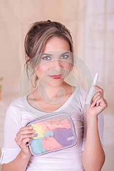 Close up of a young beautiful smiling woman holding a menstruation cotton tampon in her hand and a colorful purse inn