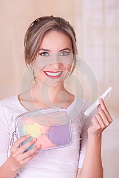 Close up of a young beautiful smiling woman holding a menstruation cotton tampon in her hand and a colorful purse inn