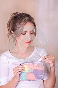 Close up of a young beautiful smiling woman holding a menstruation cotton tampon in her hand and a colorful purse in her