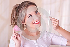 Close up of young beautiful smiling woman holding a menstruation cotton tampon in one hand and with her other hand a