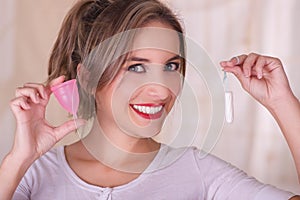 Close up of young beautiful smiling woman holding a menstruation cotton tampon in one hand and with her other hand a