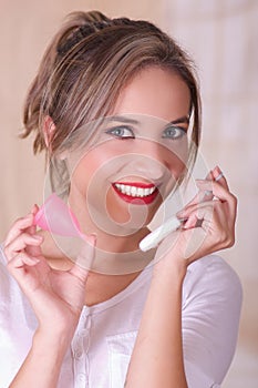 Close up of young beautiful smiling woman holding a menstruation cotton tampon in one hand and with her other hand a