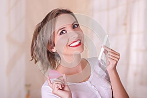 Close up of young beautiful smiling woman holding a menstruation cotton tampon in one hand and with her other hand a