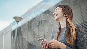 Close-up Of A Young Beautiful Sports Fitness Girl Holding A Smartphone In The Hands, Using A Fitness App. Modern City