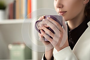 Close up of young beautiful woman hands holding hot cup of coffee