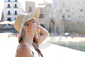 Close up young beautiful woman with hat enjoying sun on the beach. Relaxing sunbathing holidays in Cefalu, Sicily