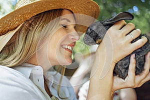 Close up of a young beautiful woman holding a small black rabbit