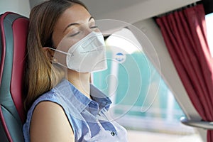 Close up of young beautiful woman with medical mask FFP2 KN95 sleeping sitting in the bus. Bus passenger traveling safely sitting