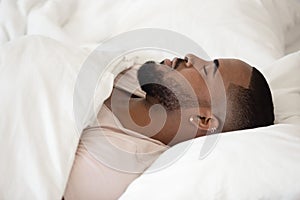 Close up young black man sleeping in bed.