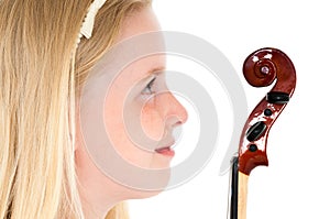 Close up of young blonde girl looking at the head of a violin on a white studio background
