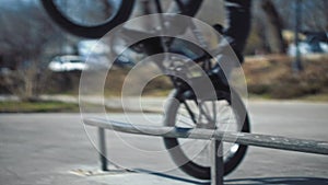 Close up of young bmx rider stops and touch pipe with his back wheel at skate park.