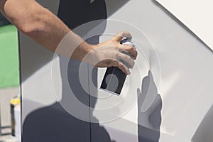 Close up with young boy doing graffiti, holding spray can with hand. Spray aerosol paint for graffiti