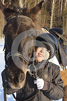 Close-up young boy hugs a horse