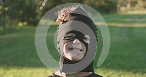 Close up of a young boy wearing a homemade ninja mask making facial expressions, no expression then smile then gritted teeth grin