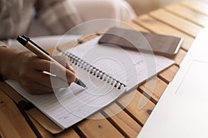 Close up young business woman hands with pen writing notes on paper. female executive sitting at table at home office. Woman`s