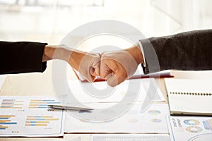 Close up of young businessman and businesswoman making a fist bump on document background