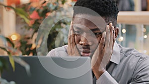 Close-up young businessman looking at laptop screen getting bad news surprised shocked man holding head found error