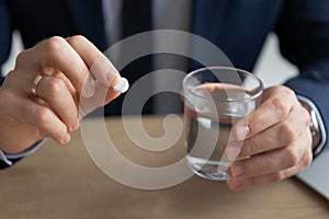 Close up young businessman thinking of taking painkiller.