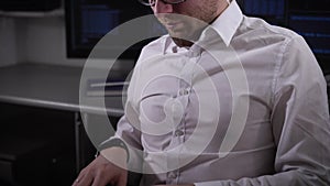 Close up of a young businessman working on laptop. IT specialist of company is sitting in the office in front of