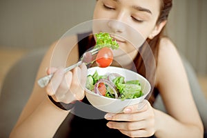 Close-up young caucasian woman eating fresh vegetable salad