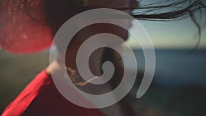 Close-up of a young Caucasian woman's hair fluttering in slow motion in the wind. Shallow depth of field. Girl in red