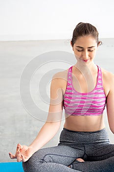 Close up of Young Caucasian woman in yoga sport clothes meditating and doing lotus yoga position.