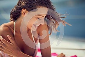 Close-up of a young cheerful girl who is relaxing on a towel while is enjoying a sunbath. Summer, sea, vacation