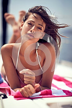 Close-up of a young cheerful sexy model who is posing for a photo while relaxing and taking a sunbath on a yacht. Summer, sea,