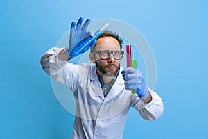 Close-up young chemist, doctor conducts chemical research isolated on blue background. Concept of pharmacology.