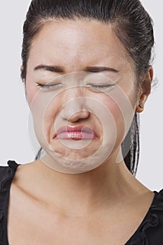 Close-up of young Chinese woman crying over white background