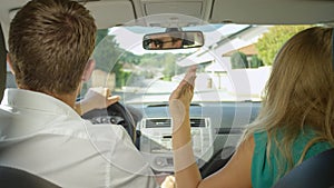 CLOSE UP: Young couple fights in the car while cruising through the suburbs.