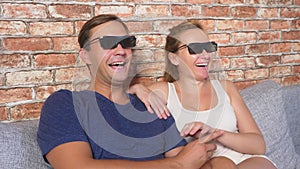 Close Up. a young couple in glasses 3d, sitting on the sofa in the living room with many emotions, watch the movie. 4k