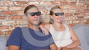 Close Up. a young couple in glasses 3d, sitting on the sofa in the living room with many emotions, watch the movie. 4k