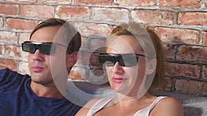 Close Up. a young couple in glasses 3d, sitting on the sofa in the living room with many emotions, watch the movie. 4k