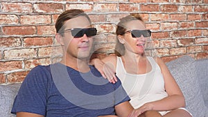 Close Up. a young couple in glasses 3d, sitting on the sofa in the living room with many emotions, watch the movie. 4k