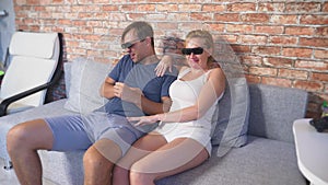 Close Up. a young couple in glasses 3d, sitting on the sofa in the living room with many emotions, watch the movie. 4k