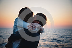 Close up of young couple hugging at sunrise beach background, summer time