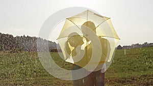 CLOSE UP: Young couple on romantic date is kissing hidden behind yellow umbrella