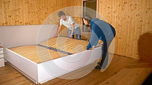 CLOSE UP: Young couple works together to assemble a large bed in their new home.