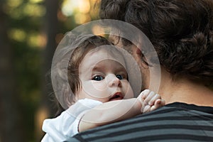 Close up of young father holding his newborn baby. Focus on the baby`s blue eyes