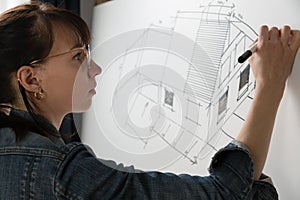 Close-up of a young female architect drawing a sketch for a new famaly home project. Concept of work on technical drawings