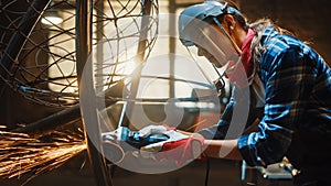 Close Up of Young Female Fabricator in Safety Mask. She is Grinding a Metal Tube Sculpture with an