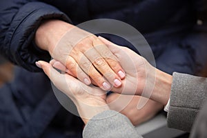 Close-up of young female hands holding senior woman hands