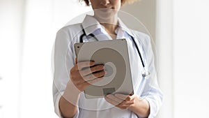 Close up young female physician using digital tablet.